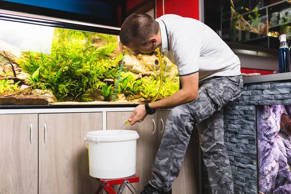 man changing water from aquarium