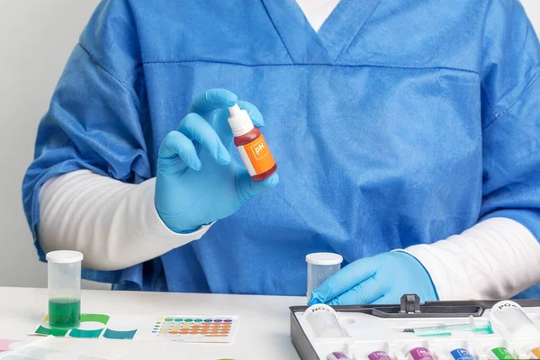 A laboratory assistant in a blue medical suit and gloves